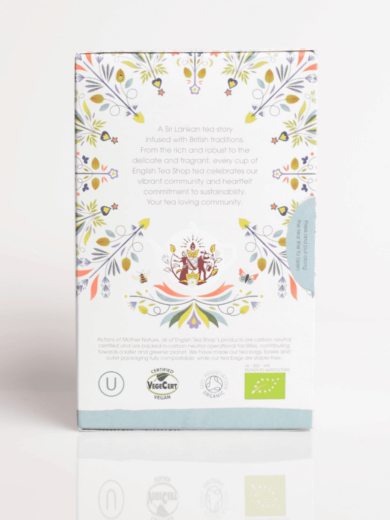 Bagpå teæske med farverigt blomstermønster, tekandeillustration og økologiske samt veganske certificeringslogoer