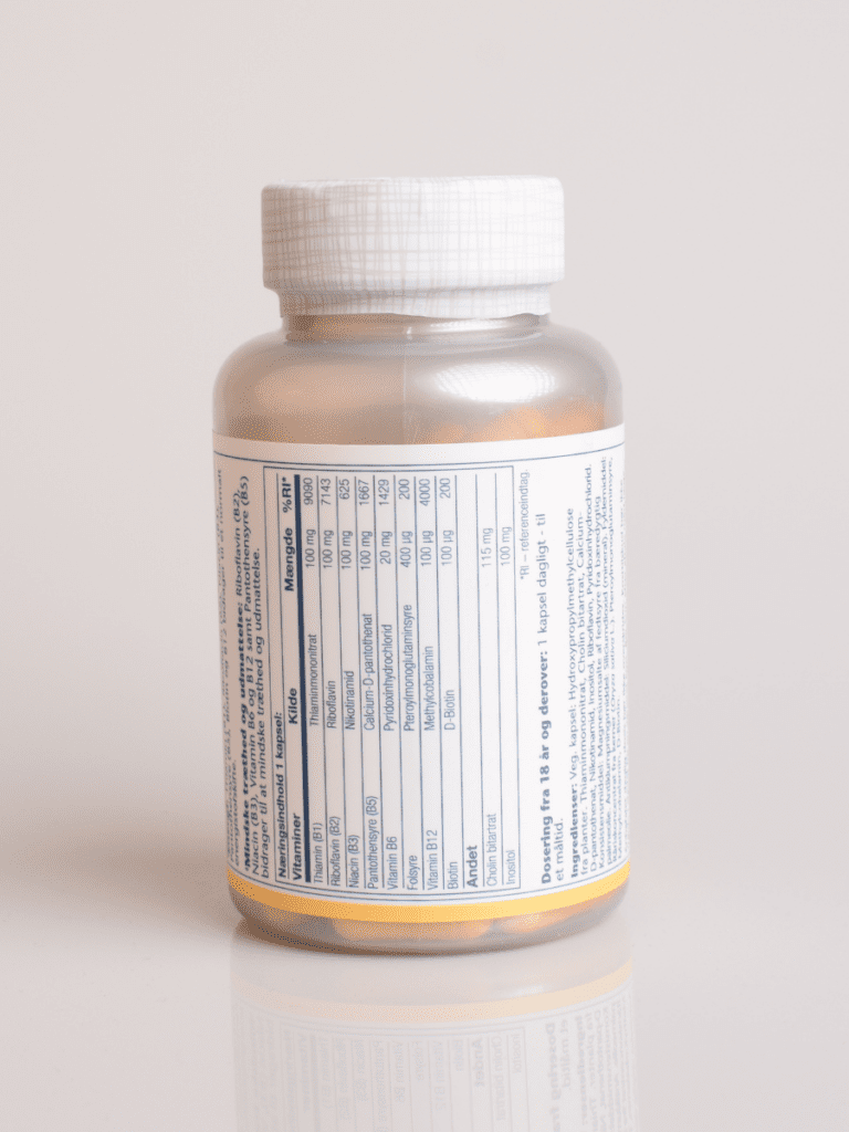 Flaske med vitamin B-kompleks kosttilskud, hvidt låg og næringstabel på etiketten