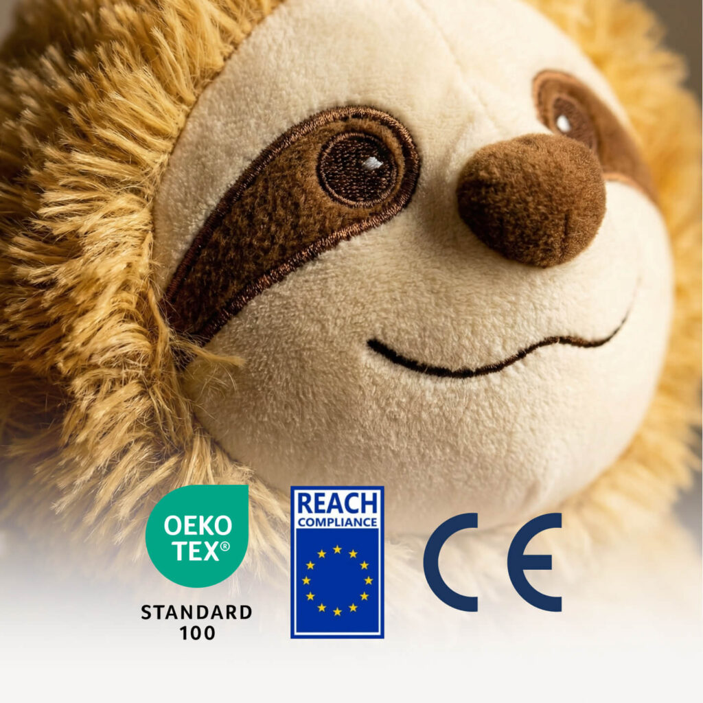 Blød beige bamse med brun næse og broderede øjne, gylden pelskant og OEKO‑TEX, REACH og CE mærker